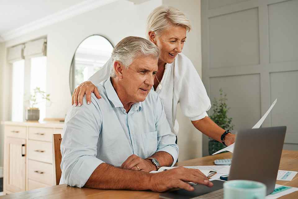 Foto: Zwei Pensionisten beim Esstisch mit einem Laptop